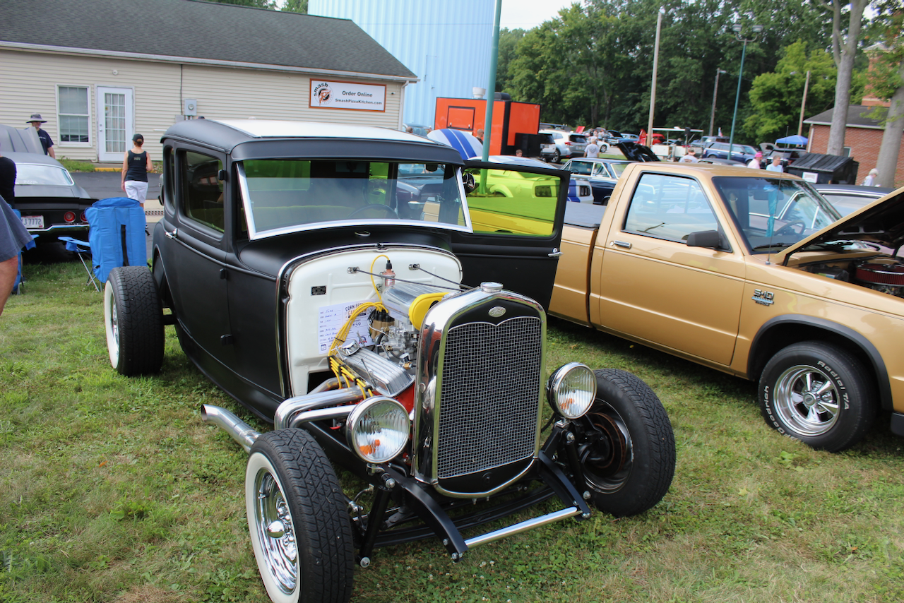 1930s Ford-style hot rod coupe, matte black, front view with exposed engine